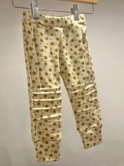 Handmade beige baby jogger pants with gold floral pattern on a hanger against a white background from Bella Rain Boutique. A handmade kids clothing boutique for kids in sizes NB-10