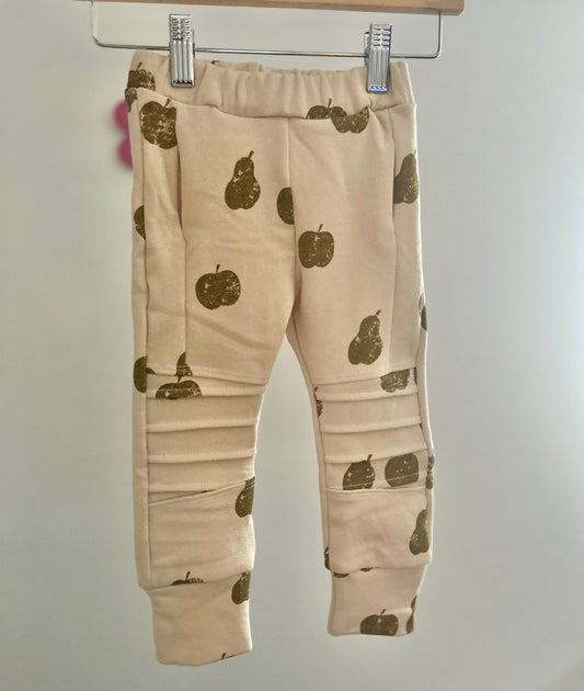 Beige baby pocket jogger pants with green pear patterns on a hanger against a plain background
